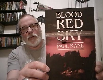 Reviewer holding copy of Blood Red Sky by Paul Kane