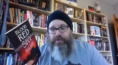 Reviewer with copy of Blood Red Sky, by Paul Kane