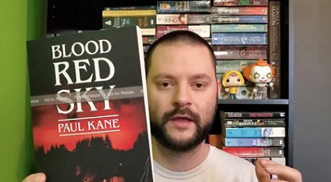 reviewer with copy of Blood Red Sky, by Paul Kane
