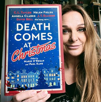 photograph of a smiling CL Taylor holding her copy of Death Comes at Christmas, edited by Marie O'Regan and Paul Kane