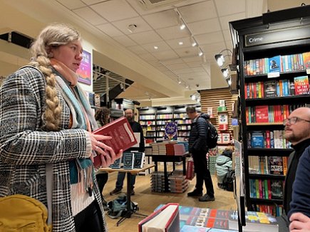 a young soman holding a copy of a book by Tom Mead, chatting to the author