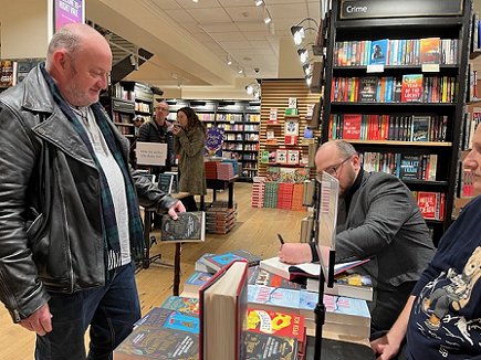 Tom Mead signing a copy of Death Comes at Christmas, edited by Marie O'Regan and Paul Kane, for a customer