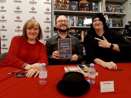 L to R: a smiling Marie O'Regan, Tom Mead and Russ Thomas. Tom is holding up a copy of Death Comes at Christmas, edited by Marie O'Regan and Paul Kane