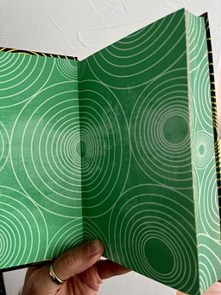 image showing the inside endpapers of Beyond and Within Folk Horror, edited by Paul Kane and Marie O'Regan. Pages are green, with a repeated pattern of gold concentric circles