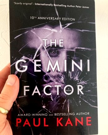 Hand holding a copy of The Gemini Factor by Paul Kane