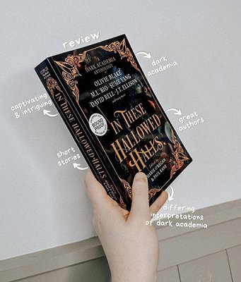 Photograph of a hand holding a copy of In These Hallowed Halls, edited by Marie O'Regan and Paul Kane, up against a white background. Text reads dark academia, great authors, captivating and intriguing, short stories, dirrering interpretations of dark academia