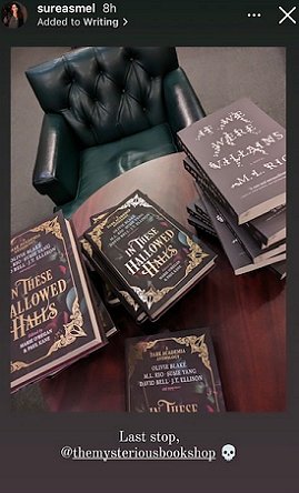 screenshot of @sureasmel Instagram. Photo shows copies of In These Hallowed Halls, edited by Marie O'Regan and Paul Kane, and If We Were Villains by M L Rio, on a wooden table. An empty green leather armchair is behind the table