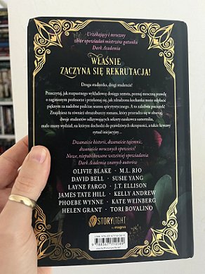 photograph of a man's hand holding a copy of the Polish edition of In These Hallowed Halls, edited by Marie O'Regan and Paul Kane, to show the back cover