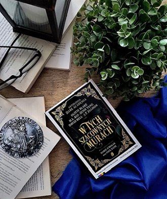 photograph showing Polish cover for In These Hallowed Halls, edited by Marie O'Regan and Paul Kane. Also featured is a jade plant, a pair of glasses, and several typed pages and a blue cloth.