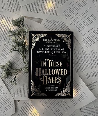 photograph of a copy of In These Hallowed Halls, edited by Marie O'Regan and Paul Kane, lying on loose typed pages, with a sprig of leaves with white flowers