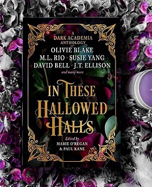 Image of a copy of In These Hallowed Halls, edited by Marie O'Regan and Paul Kane, lying on a purple and grey background, alongside a white feather and a purple candle in a white container
