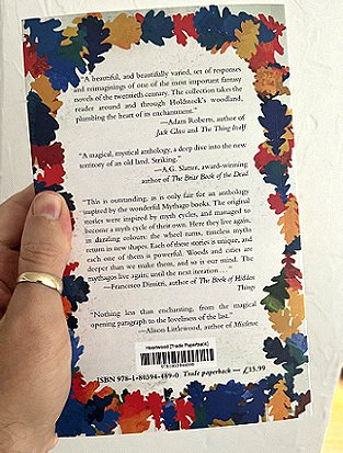 photograph of a man's hand holding up a copy of Heartwood, edited by Dan Coxon, to show the back cover