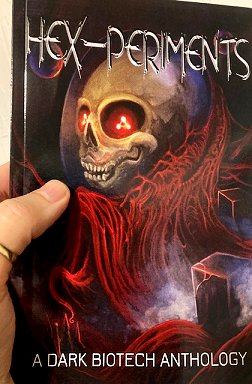 Man's hand holding a book: Hex-periments. A dark biotech anthology