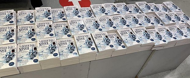 Display of multiple copies of The Other Side of Never, edited by Marie O'Regan and Paul Kane, on a table