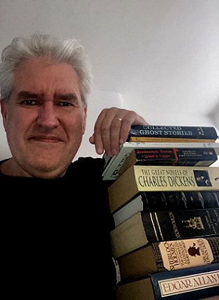 Paul Kane seated next to a pile of books he found inspirational