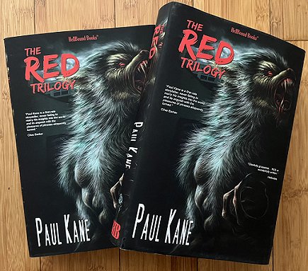 photograph of two copies of The RED Trilogy on a wooden surface