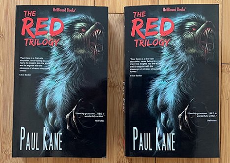 photograph showing two copies of The Red Trilogy by Paul Kane, lying on a wooden surface