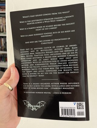 photograph of a man's hand holding a copy up of The Roads Less Travelled by Paul Kane, to show the back cover