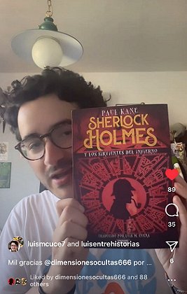 screenshot of translator Luis Cuena holding up a copy of the Spanish edition of Sherlock Holmes and the Servants of Hell, by Paul Kane