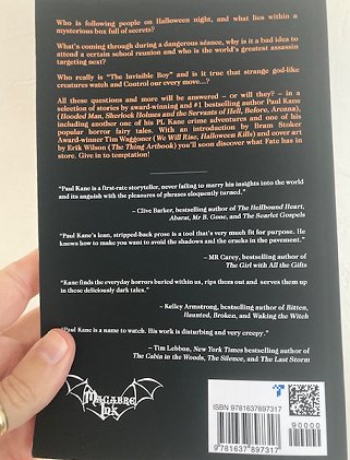Hand holding up the back cover of Tempting Fate by Paul Kane