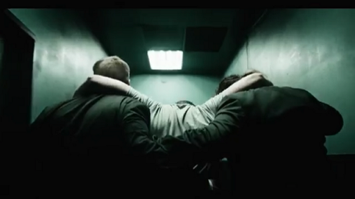 Still from The TOrturer, unconscious man being carried by two other men