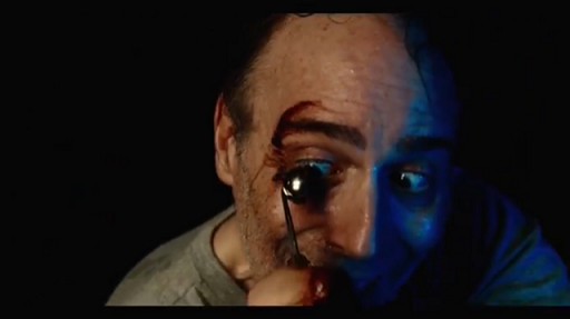 Still from The Torturer, injured man - device approaching his eye