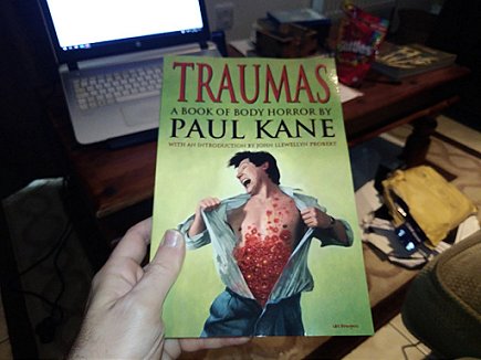 Person holding copy of Traumas by Paul Kane