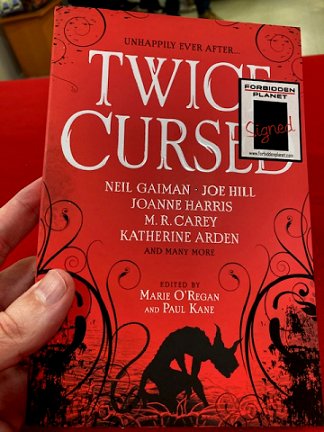 Hand holding a signed copy of Twice Cursed, edited by Marie O'Regan and Paul Kane