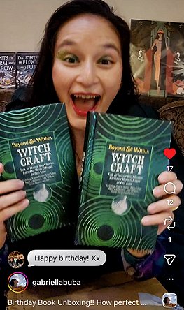photograph of a smiling Gabriella Buba holding two copies of Beyond and Within Witchcraft, edited by Marie O'Regan and Paul Kane