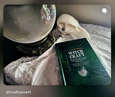 photograph of a copy of Beyond and Within Witchcraft, edited by Marie O'Regan and Paul Kane, lying on a cream cloth edged with lace. In the background is a bird's skull and a crystal ball
