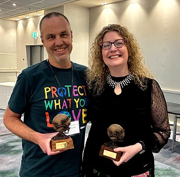 Photograph showing World Fantasy Award-winners Dan Coxon (L) and Maura McHugh (R) smiling and showing their awards