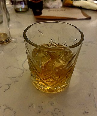 photograph showing a tumbler of whiskey on a marble surface