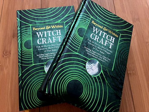 photograph showing two copies of Beyond & Within: Witchcraft, edited by Marie O'Regan and Paul Kane, on a wooden surface